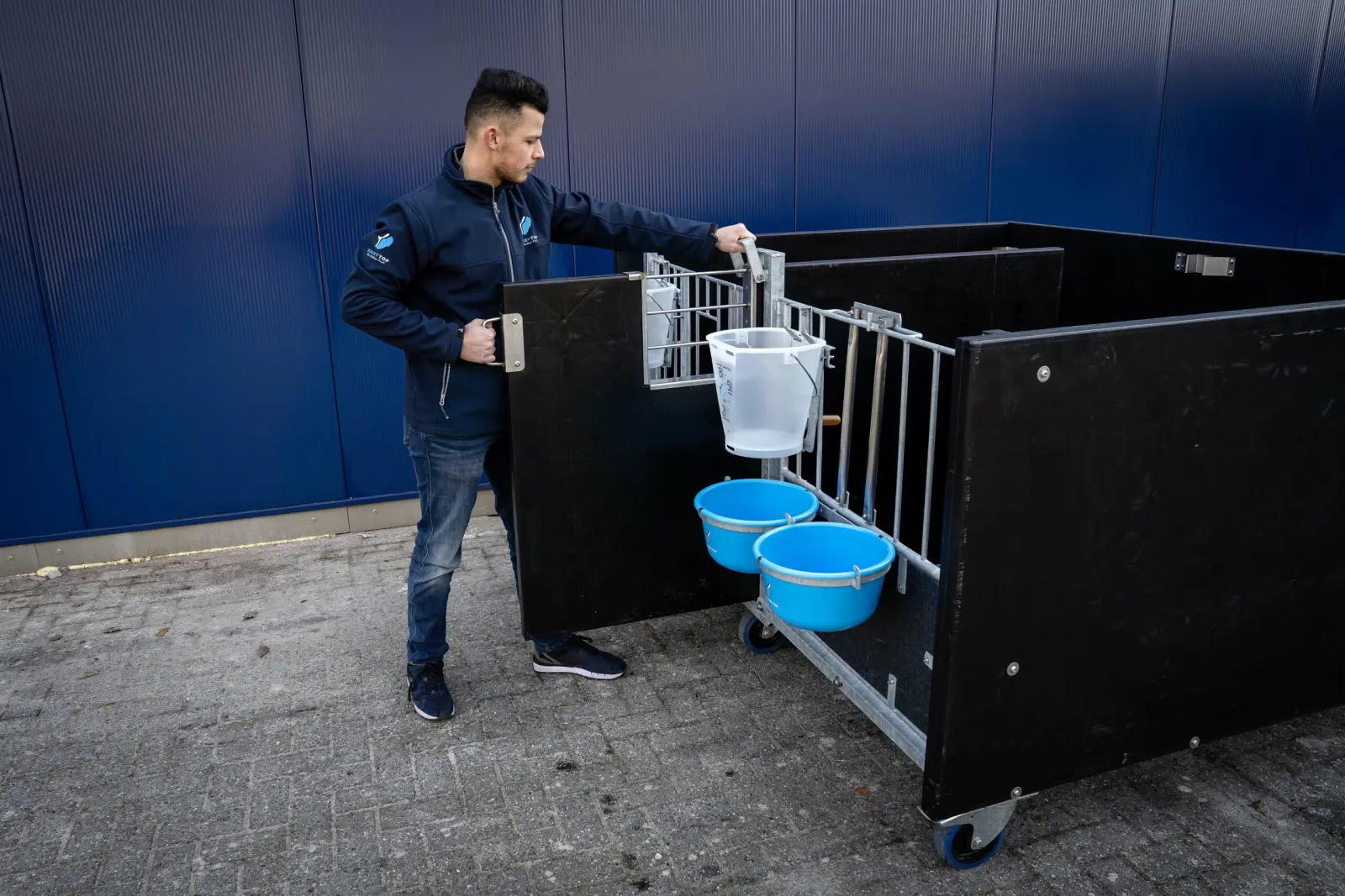 Calf pen on wheels with buckets on the front gate