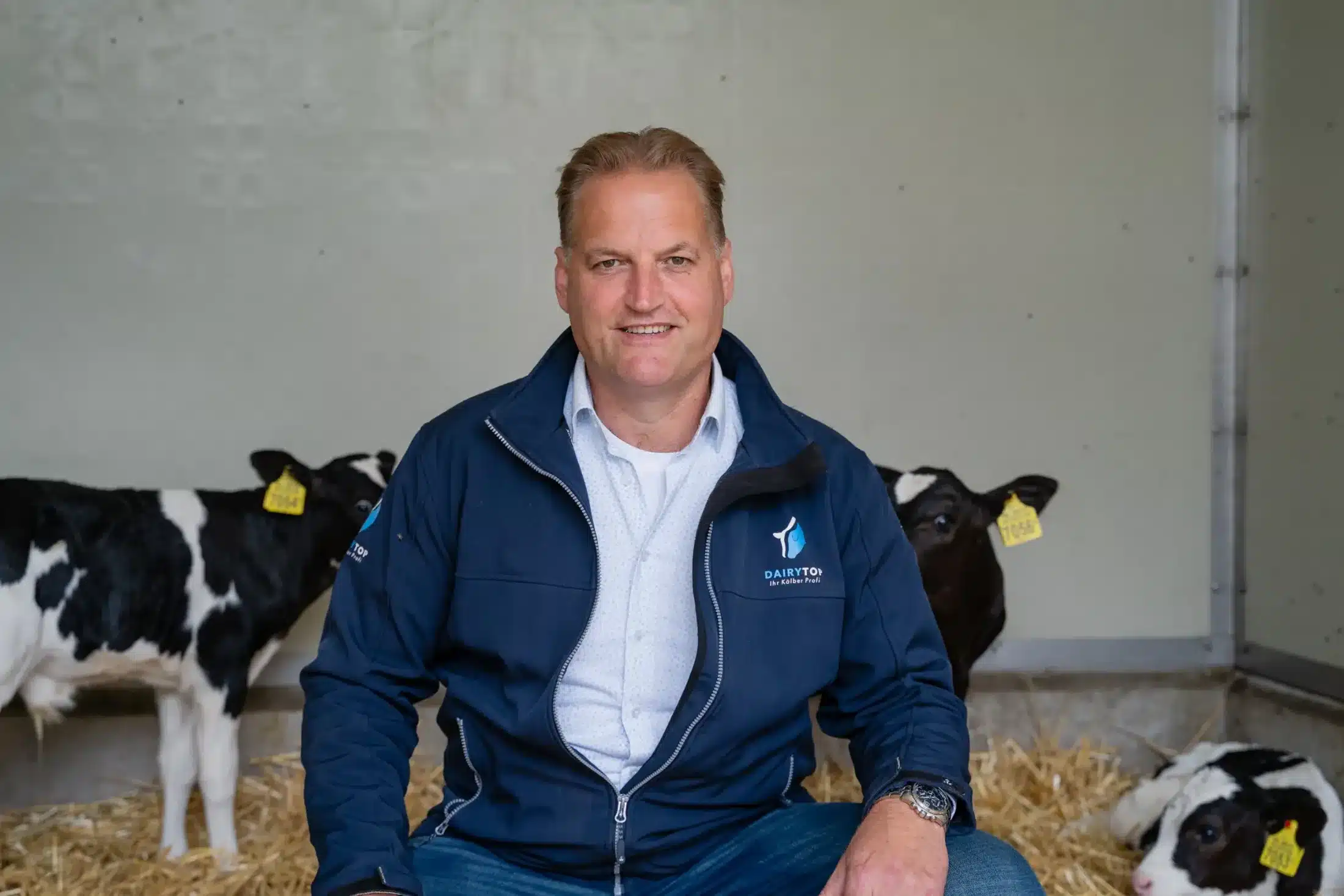 Adviseur van DairyTop zit tussen de jonge kalveren op het stro