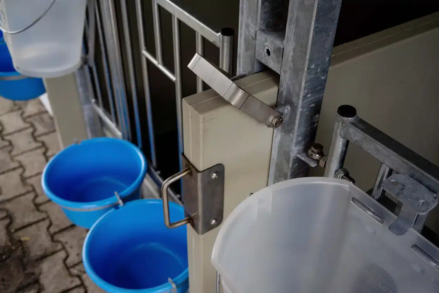Tussenwand met handgreep en klemsluiting aan de verzinkte staander, met drinkemmers aan het fronthek